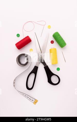 yellow, red and green thread coils, scissors, pin and tape measure on white background, sewing, handmade concept, design for seamstress and tailor, tr Stock Photo