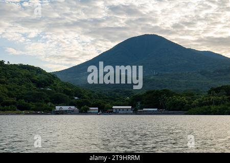 Coastline Seen From Afar with a Volcanic Mountain, Lush Vegetation Forest, Beach, and Houses with a Calm Ocean Stock Photo