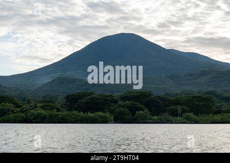 Coastline Seen From Afar with a Volcanic Mountain, Lush Vegetation Forest and Some Electric Lines and Poles with a Calm Ocean Stock Photo