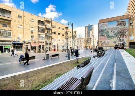 People walk down Jaffa Street and sit on the stairs and benches at the Clal Center on a spring day in Jerusalem. Stock Photo