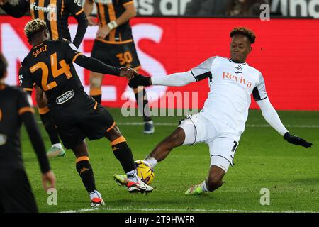 Swansea, UK. 25th Nov, 2023. Jamal Lowe of Swansea City is tackled by Jean Michael Seri of Hull City (24) .EFL Skybet championship match, Swansea city v Hull City at the Swansea.com Stadium in Swansea, Wales on Saturday 25th November 2023. this image may only be used for Editorial purposes. Editorial use only, pic by Andrew Orchard/Andrew Orchard sports photography/Alamy Live news Credit: Andrew Orchard sports photography/Alamy Live News Stock Photo