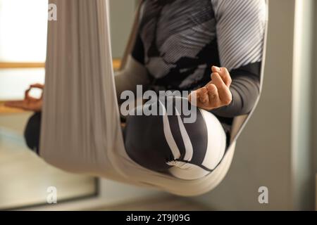 Man meditating in fly yoga hammock indoors, closeup Stock Photo