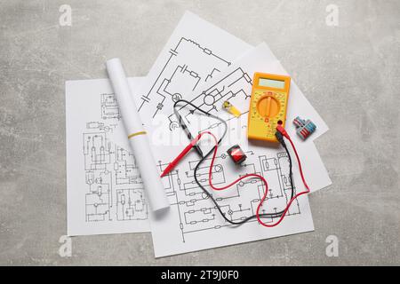Wiring diagrams, digital multimeter and connectors on grey table, flat lay Stock Photo