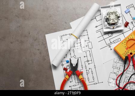 Wiring diagrams, digital multimeter and other electrician's equipment on grey table, top view. Space for text Stock Photo