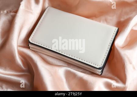 Stylish presentation of leather purse on silk fabric, closeup Stock Photo