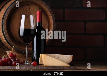 Delicious wine, cheese, grapes and wooden barrel on table against brick wall. Space for text Stock Photo