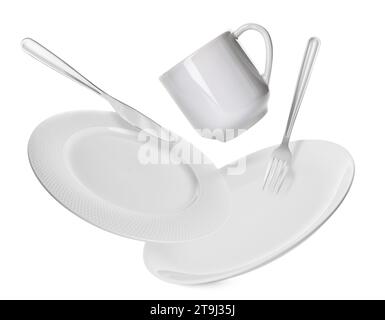 Clean plates, fork, knife and cup falling on white background Stock Photo
