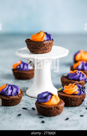 Brownie  chocolate cupcakes with ghost cream decor and sprinkles on a slate board on a gray background. Happy Halloween concept. American culture and Stock Photo