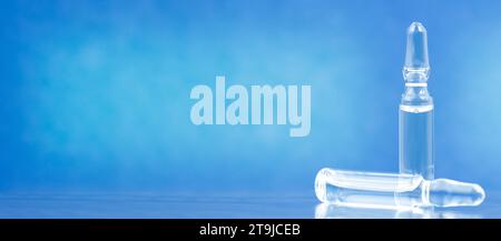 Two medical ampoules with solution for injection on blue background. Space for text. Stock Photo