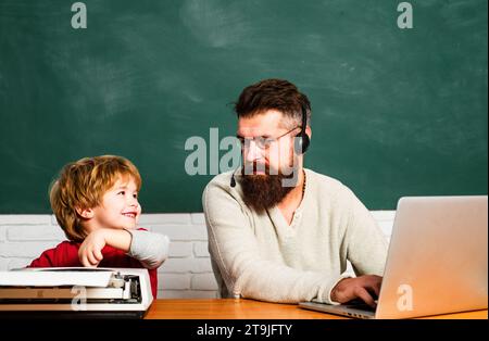 Man teacher play with preschooler child. Back to school. Tutoring. Man teaches child. Daddy and son together. Teacher helping pupils studying on desks Stock Photo