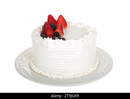 White buttercream frosted vanilla cake topped with fresh strawberries, boysenberries and blueberries sitting on a decorative porcelain plate. Isolated Stock Photo