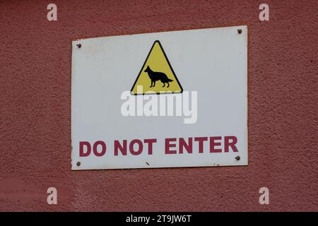 Do not enter warning sign . White square . Yellow triangle shape. Black color body, beware of dog. Red Background. Part of the door. Stock Photo