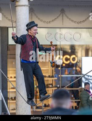 Man balancing on a tightrope while playing a fiddle Stock Photo