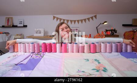 Happy woman seamstress in her studio working on a new collection of threads Stock Photo
