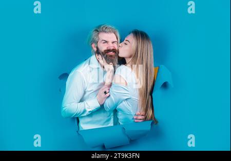Couple through hole in blue paper, copy space for text or slogan. Discount and sale, people hole background. Surprised couple of bearded man and happy Stock Photo