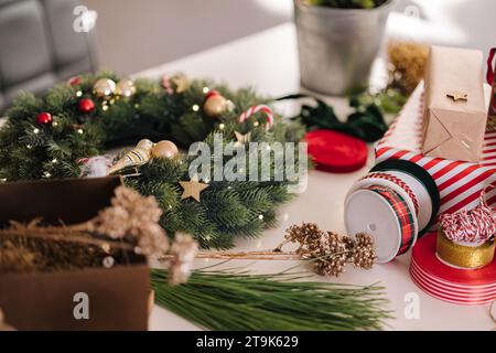 Preparing for Christmas holidays. Decor on table. Wreath and fir tree. Different ribbons Stock Photo