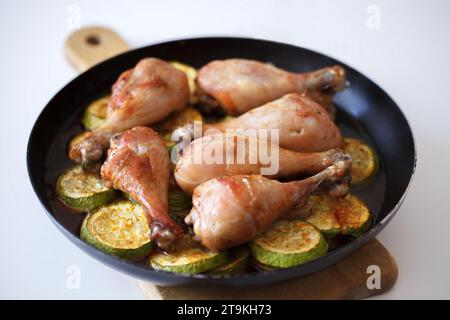 Fried chicken legs in a frying pan with zucchini slices in oil Stock Photo