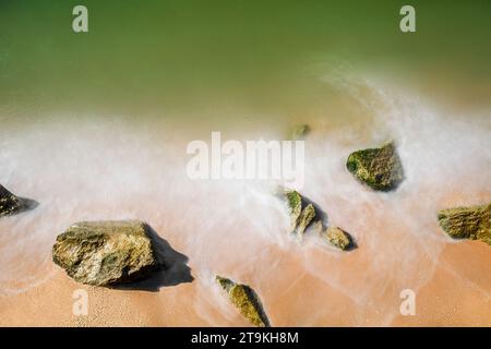 Sea sandy beach with stones, blurry water movement. Stock Photo