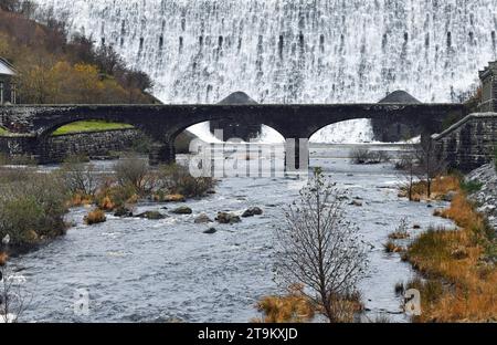 Looking up to the Caban Coch Reservoir in the Elan Valley along the River or Afon Elan where a large amount of water is cascading over the edge Stock Photo