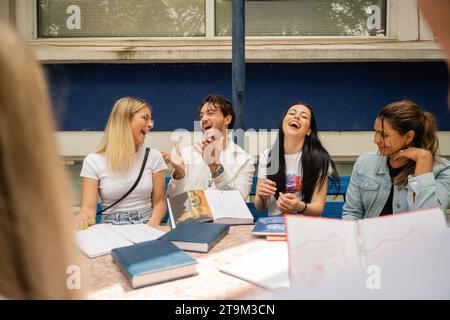 A diverse group of university students discussing exam answers and exchanging ideas outdoors on campus. Stock Photo