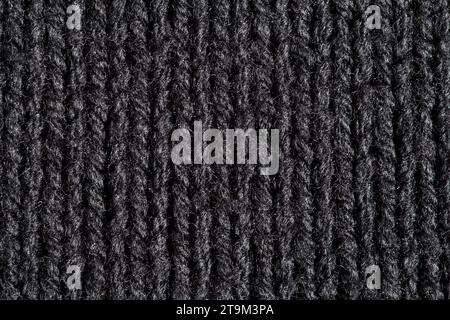 Knitted fabric made of black wool threads, background structure, close-up macro view Stock Photo