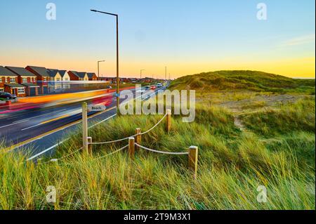 Evening rush hour traffic along Clifton Drive next to Fylde coast sand dunes on the Lancashire coast Stock Photo