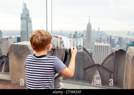 Boy looking through binoculars at the top of the Rockefeller center in New York City, United States of America. Stock Photo