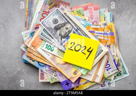 2024 in finance, Business concept, Big pile of money, All world currencies and yellow sticky note with the year 2024, World economic situation, armed Stock Photo