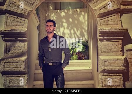 A man standing in a doorway with his hands in his pockets. The Contemplative Man: Pondering Life's Uncertainties in the Doorway Stock Photo
