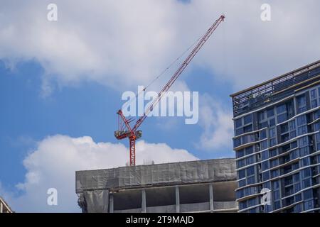Tower cranes and unfinished buildings on background of blue sky with white clouds. Housing construction, apartment blocks in city Stock Photo