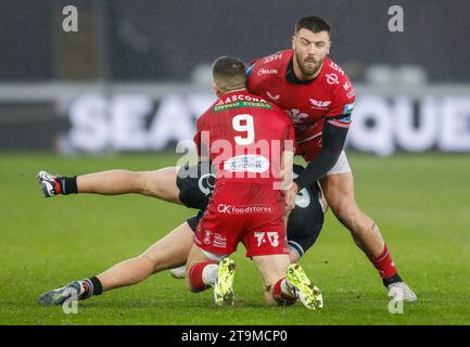 Swansea, UK. 26th Nov, 2023. Keiran Williams of the Ospreys tackled by Gareth Davies of the Scarlets (9). United Rugby Championship, Ospreys v Scarlets at the Swansea.com stadium in Swansea, South Wales on Sunday 26th November 2023. pic by Geraint Nicholas/Andrew Orchard sports photography/Alamy Live news Credit: Andrew Orchard sports photography/Alamy Live News Stock Photo