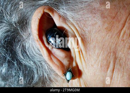 Senior adult woman with hearing aid to increase her hearing ability Stock Photo