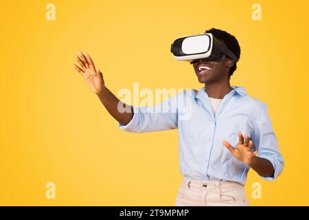 Smiling young african american woman student in casual and vr glasses, controls copy space Stock Photo