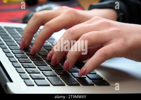Woman typing on laptop keyboard, hands on keyboard close up, floating focus Stock Photo
