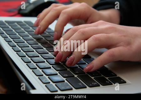 Woman typing on laptop keyboard, hands on keyboard close up, floating focus Stock Photo