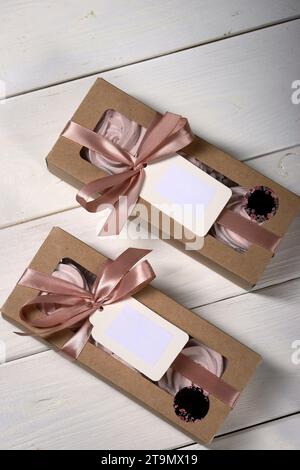 Two boxes of homemade zephyr. Zephyr flowers. Craft packaging tied with ribbon. Labels with text field. Shot from above, on white boards. Stock Photo