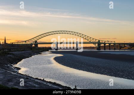 Sunset behind the Silver Jubilee Bridge (opened 1961), which crosses the River Mersey and the Manchester Ship Canal, linking Runcorn and Widnes Stock Photo