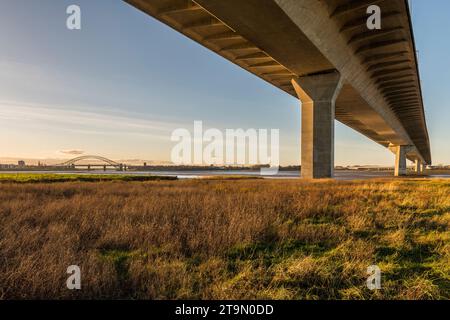 A view underneath the Mersey Gateway Bridge, which crosses the River Mersey and the Manchester Ship Canal, with the Silver Jubilee Bridge beyond Stock Photo