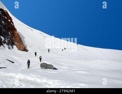 climbers, hikers, trekkers or mountaineers on white snow plain or glacier, way to mount Everest, Nepal Himalayas mountains Stock Photo