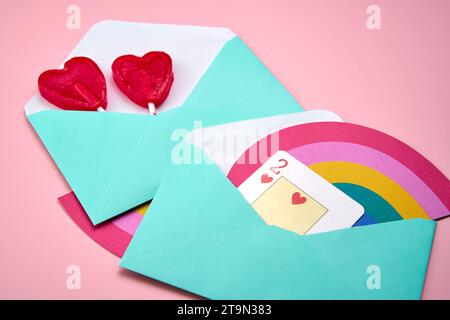 Love letters with rainbow and heart-shaped lollipops on top of a pink background Stock Photo