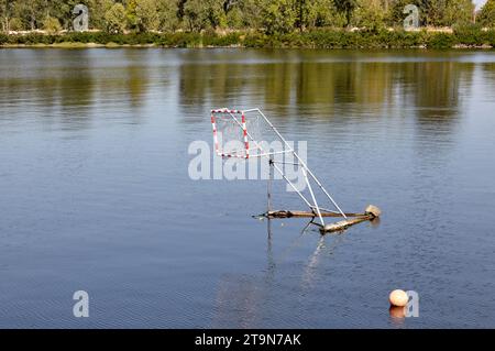 Water polo goal net and ball in water, outdoors. Leisure activity in the water zone in park Stock Photo