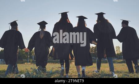 Graduate students walking through an evening meadow at sunset. Stock Photo