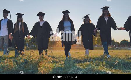 Graduate students walking through an evening meadow at sunset. Stock Photo