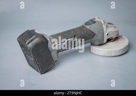 Battery operated angle grinder with grinding abrasive disc mounted. Cordless angle grinder isolated on gray. Stock Photo