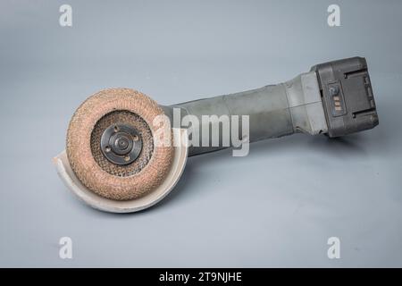 Battery operated angle grinder with grinding abrasive disc mounted. Cordless angle grinder isolated on gray. Stock Photo