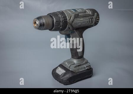 Cordless battery powered drill or screwdriver. Practical machine without electric cable for drilling and screwing in screws. Isolated on gray. Stock Photo