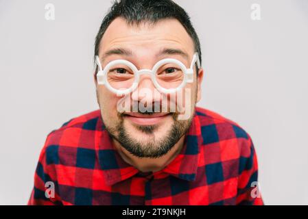 Funny portrait of a man with glasses. Cheerful bearded science geeks looking at the camera close up. Сomic nerd close-up portrait. Stock Photo