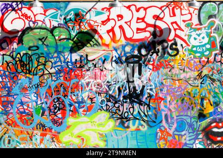 Bright, colorful graffiti, tagging, vandalism, and antisocial behavior on an urban wall. Stock Photo