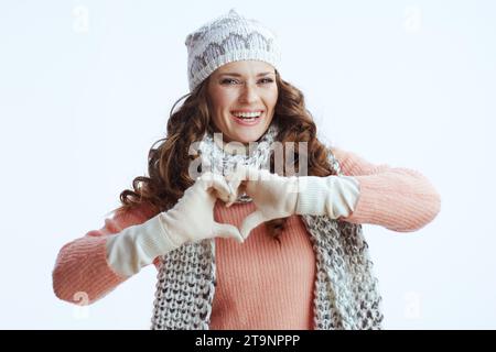 Hello winter. happy stylish woman in sweater, mittens, hat and scarf showing heart shaped hands isolated on white. Stock Photo