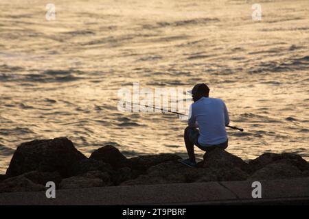 Fishermen spend the late afternoons daily at the seafront in Cartagena, Colombia Stock Photo